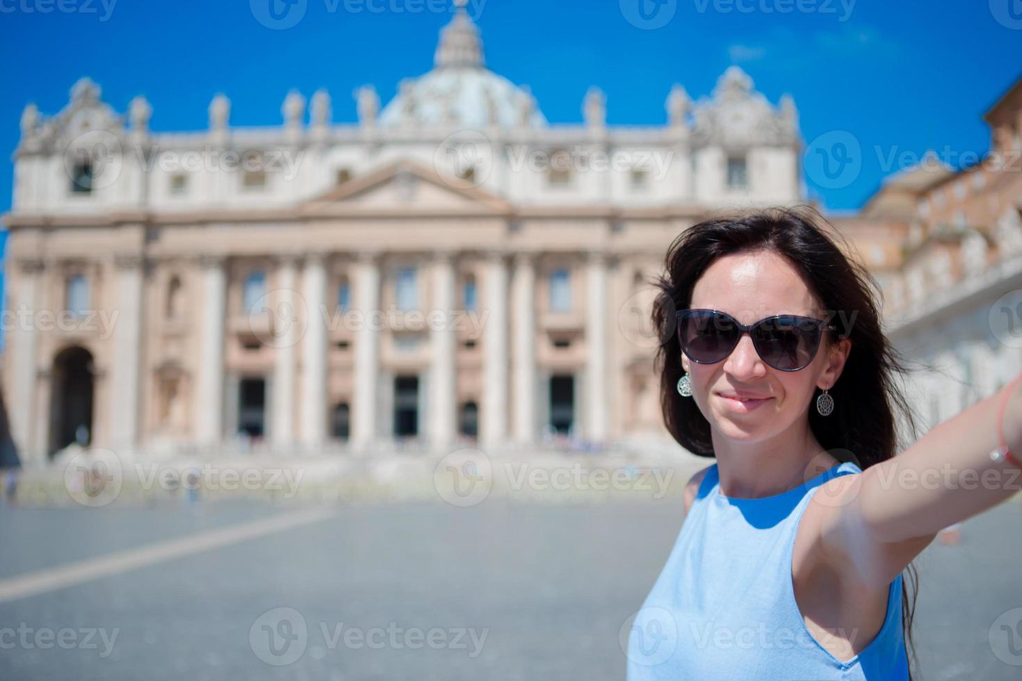 Happy young woman taking selfie at St. Peter's Basilica church in Vatican city, Rome. Beautiful caucasian tourist making selfie photo picture on european vacation in Italy.