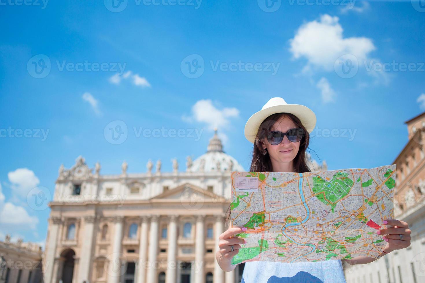 mujer joven feliz con mapa de la ciudad en ciudad del vaticano y st. basílica de san pedro, roma, italia. viaje mujer turista con mapa al aire libre durante las vacaciones en europa. foto