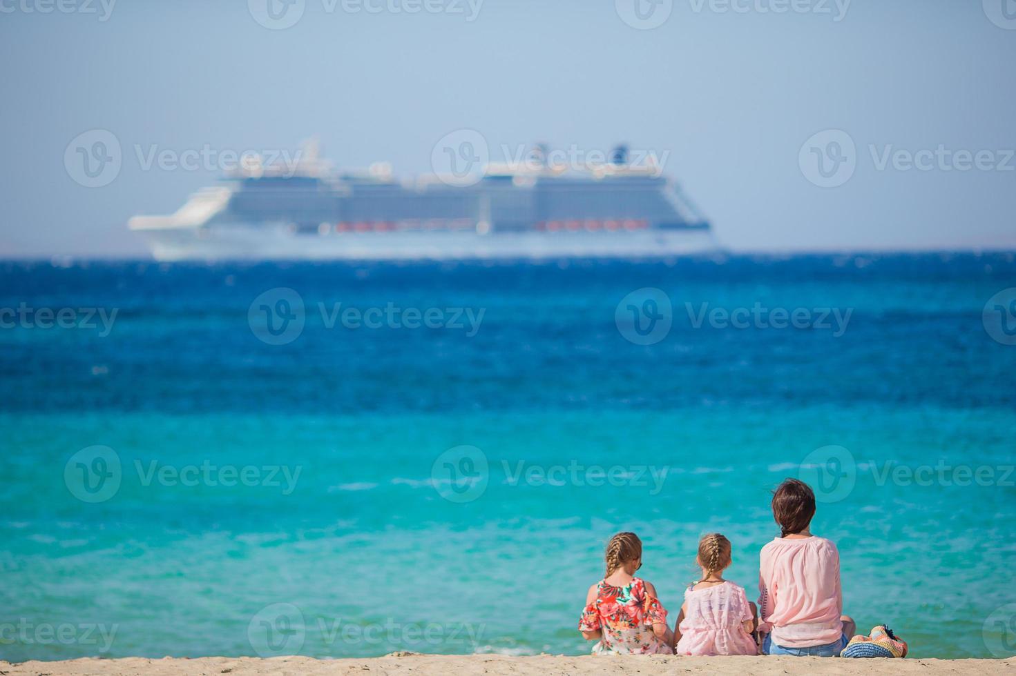 Young happy mother and her adorable daughters at exotic beach on sunny day photo