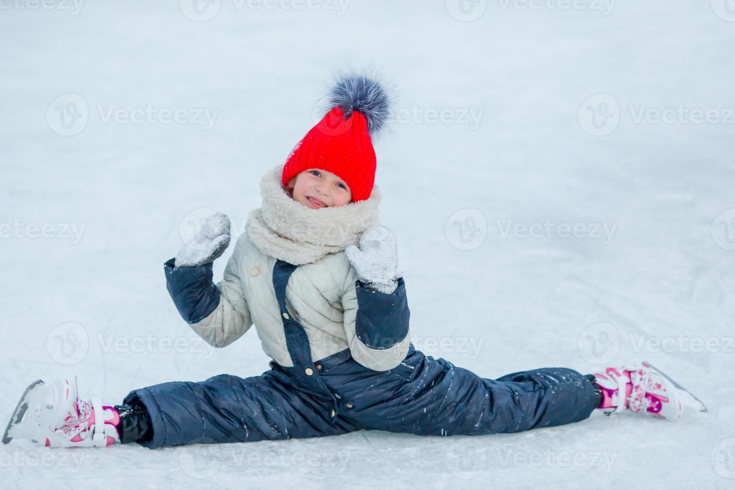 Little adorable girl sitting on ice with skates after fall photo