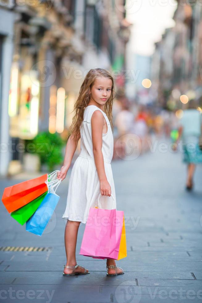 Adorable little girl walking with shopping bags outdoors in Rome. Fashion toddler kid in Italian city with her shopping photo