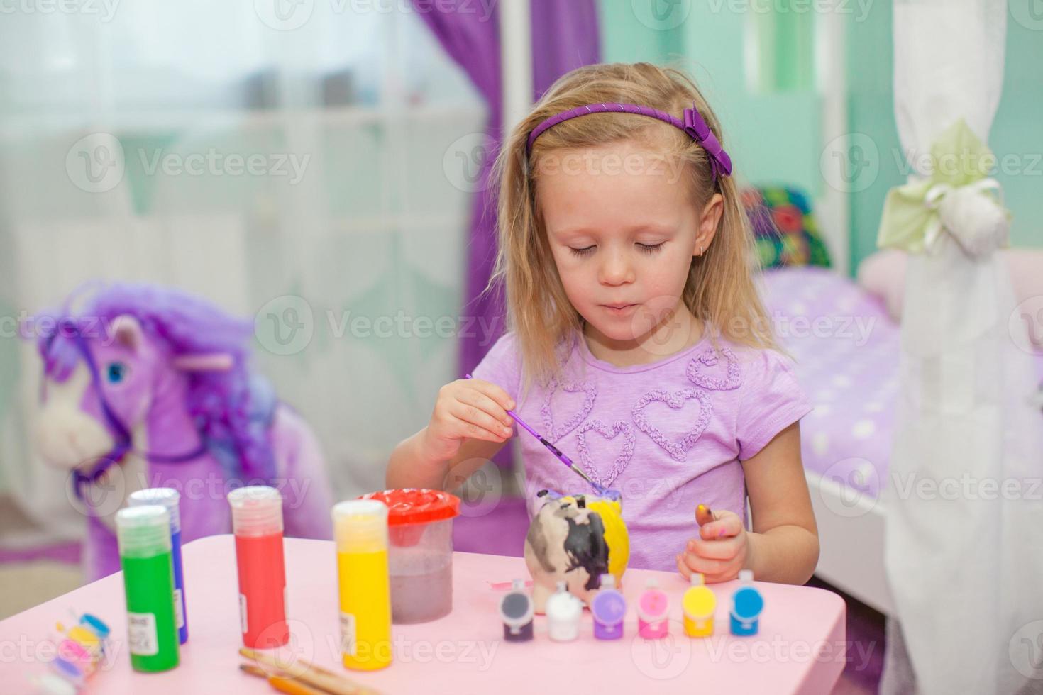 Little beautiful girl draws paints on the table photo