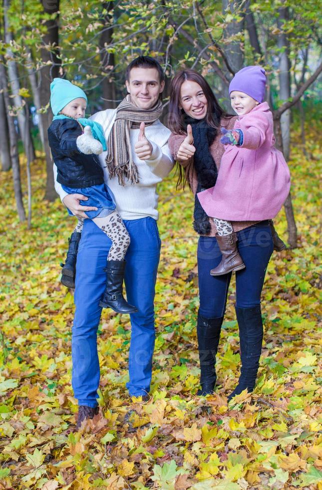 familia de cuatro personas disfrutando de las vacaciones de otoño y mostrando un pulgar hacia arriba foto