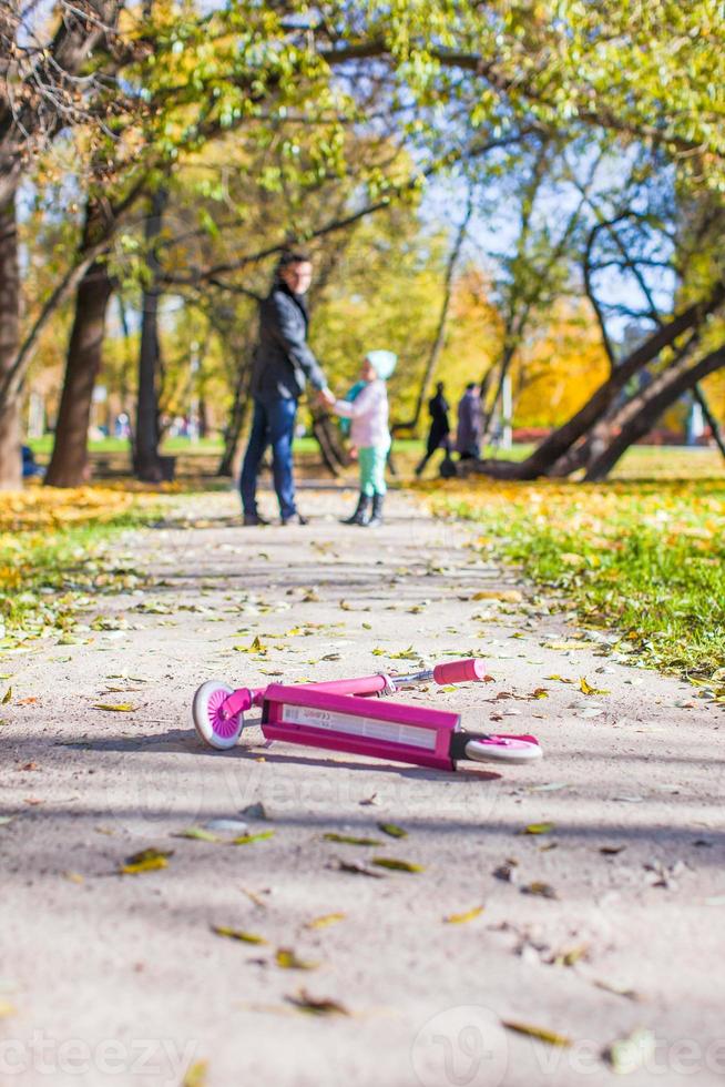 adorable niñita con padre feliz caminando en el parque de otoño en un día soleado foto