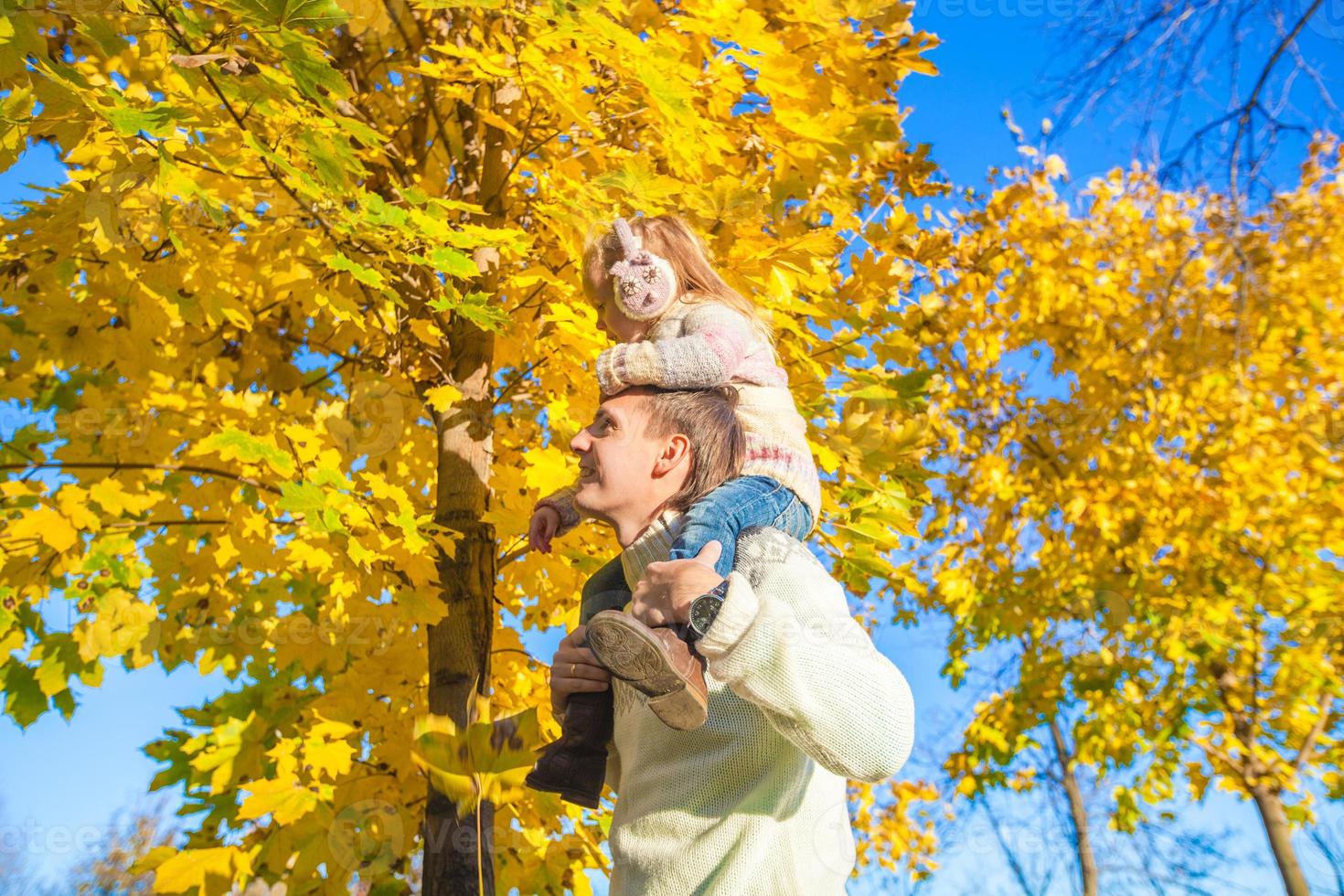 niña con padre feliz divirtiéndose en el parque de otoño en un día soleado foto