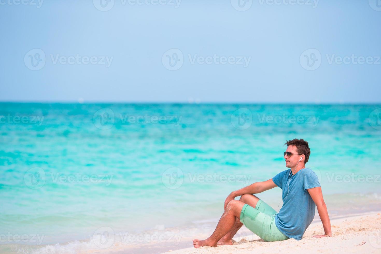 Young man enjoying the music on white beach photo