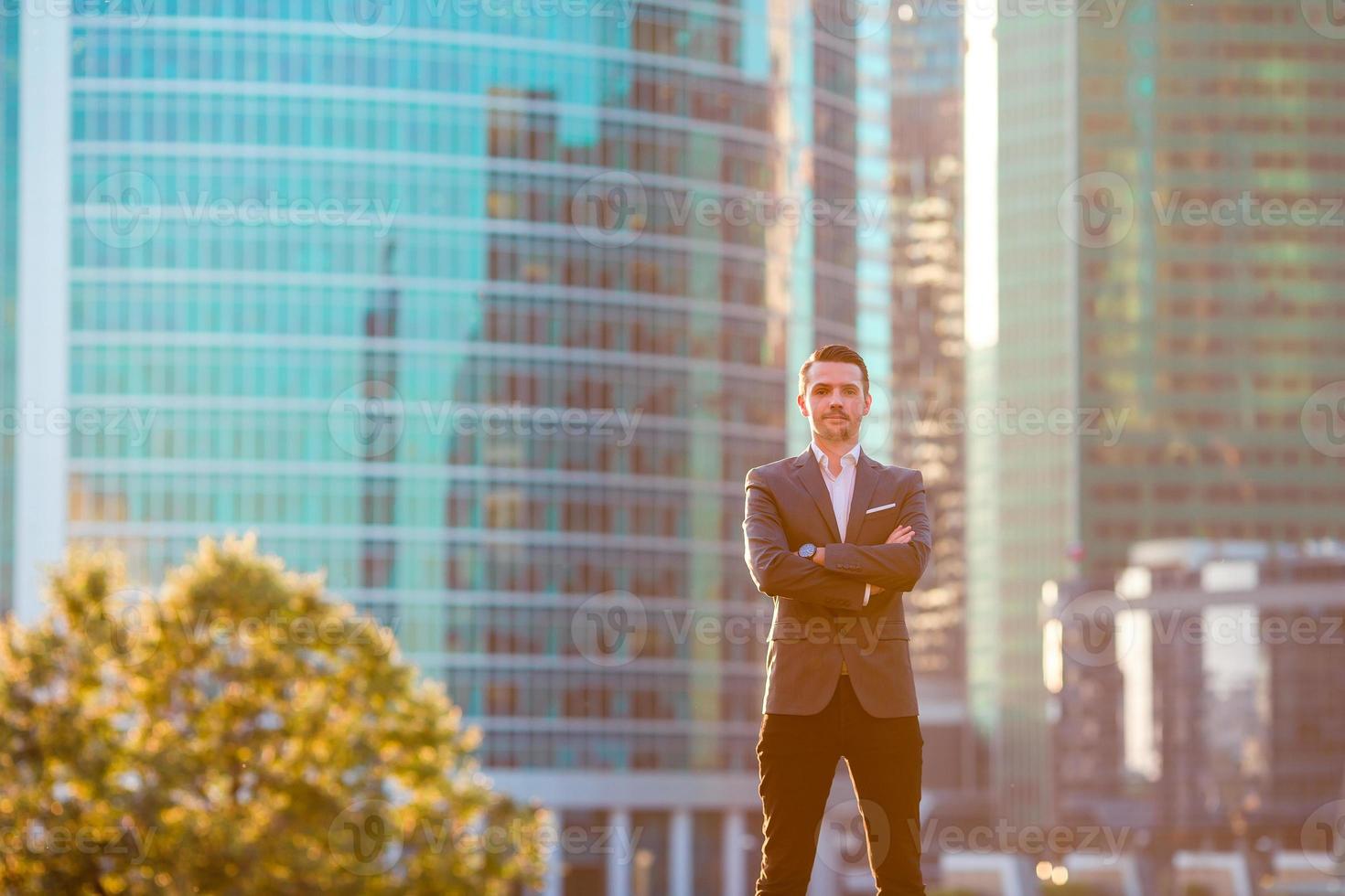 Businessman looking on copy space while standing against glass skyscraper photo