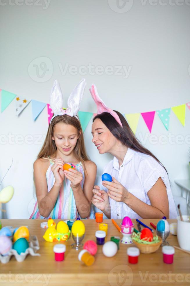 madre y su pequeña hija pintando huevos. familia feliz preparándose para pascua. foto