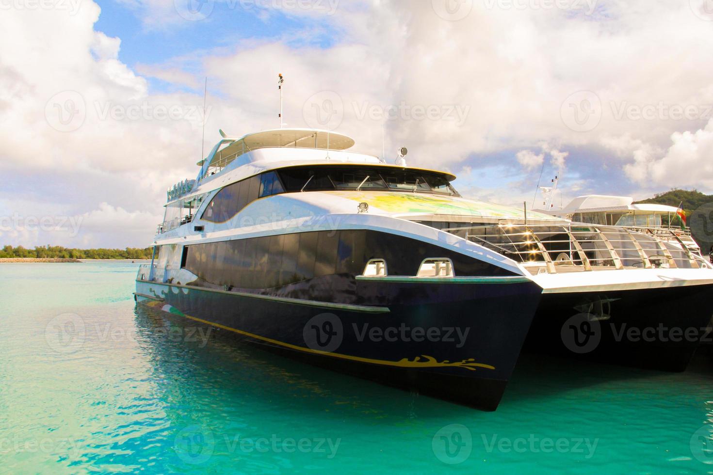 Small boat and cruiser off the coast at tropical island in turquoise water photo