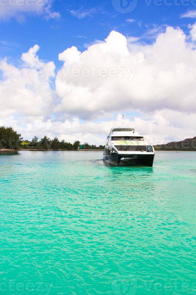 Small boat and cruiser off the coast at tropical island in turquoise water photo