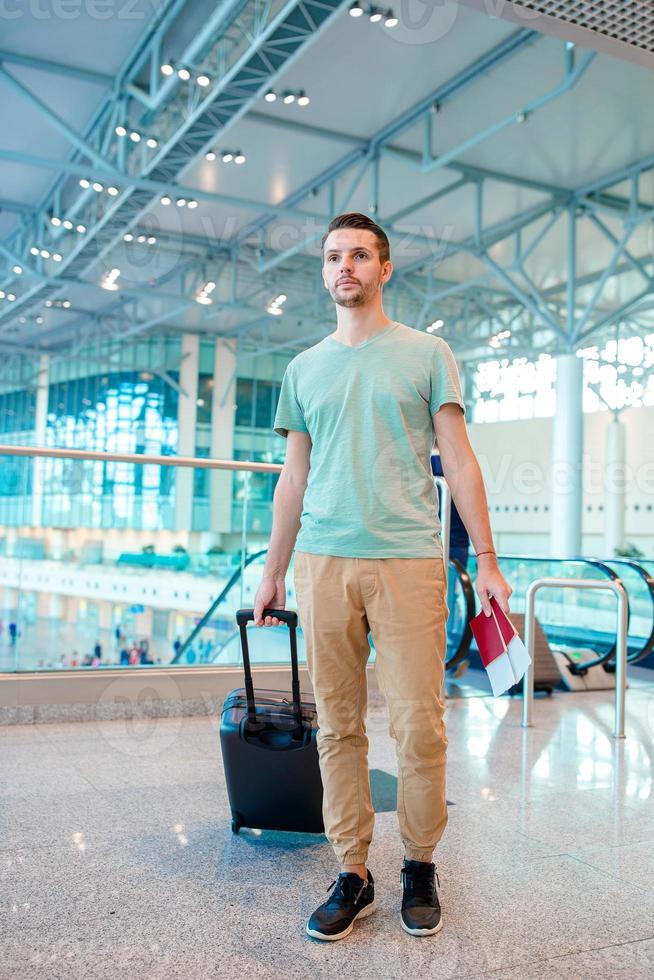 Young man in an airport lounge waiting for flight aircraft. photo