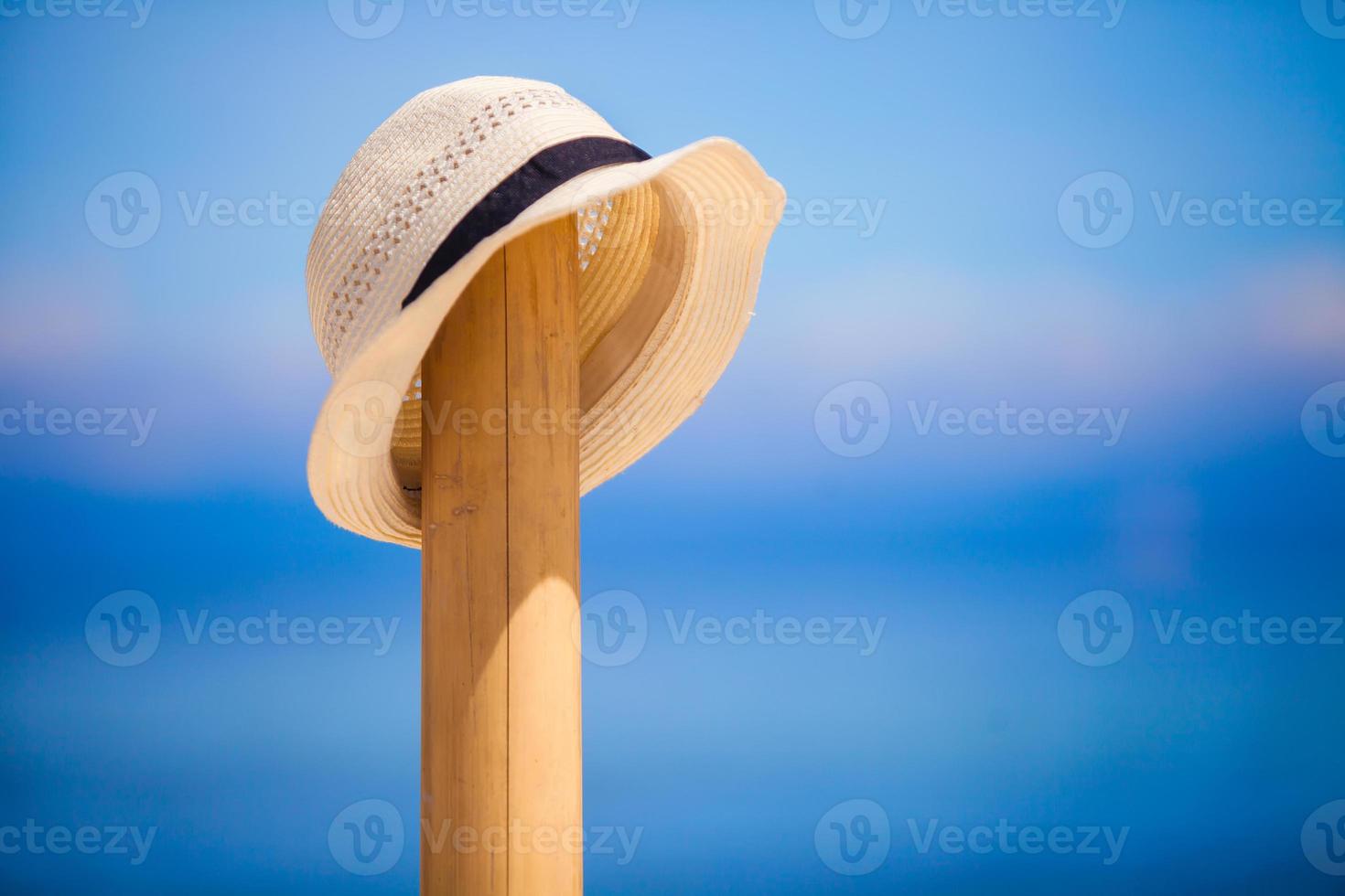 Straw hat at wooden fence on the white sandy beach photo