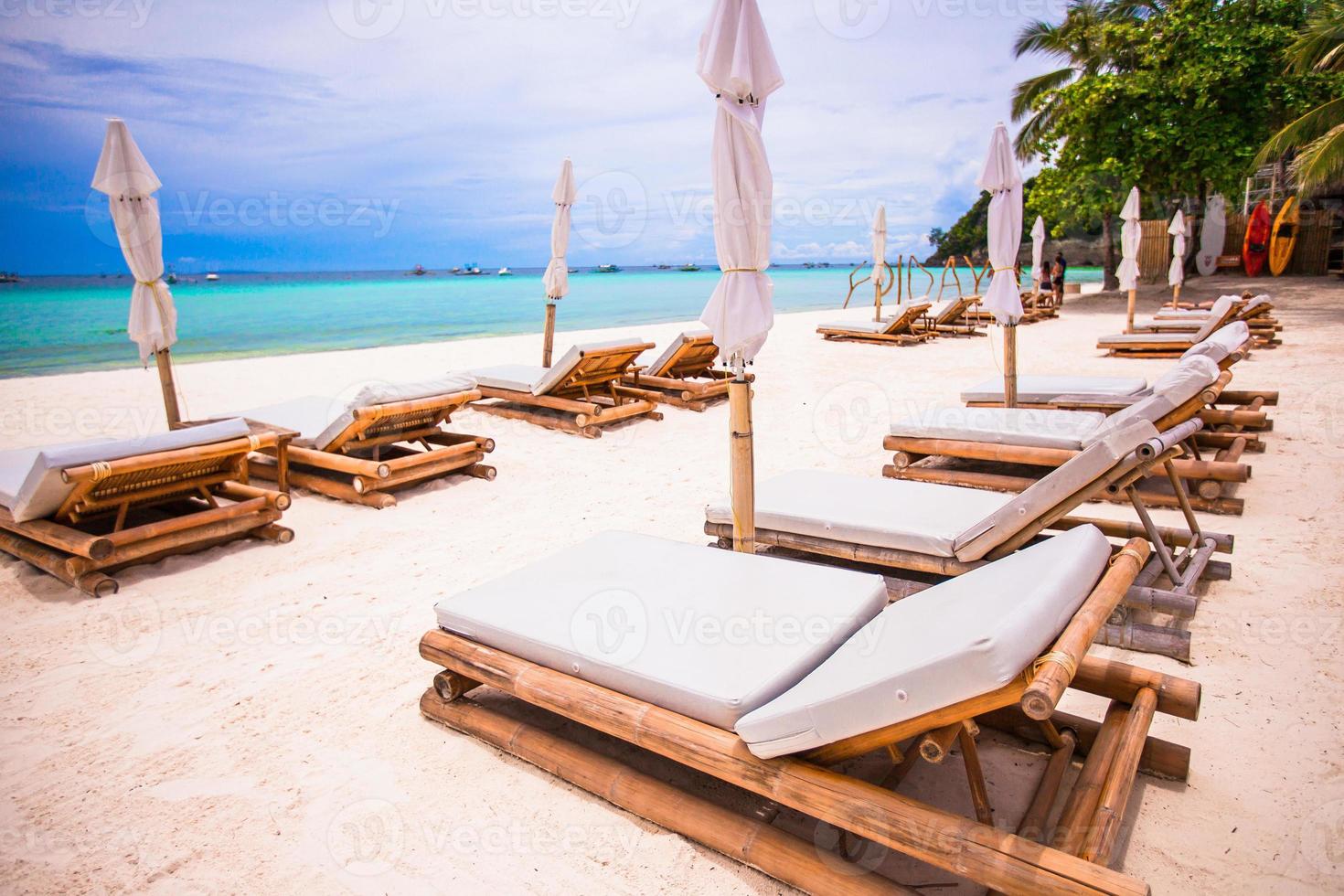 Beach beds and umbrellas on exotic tropical white sandy beach photo