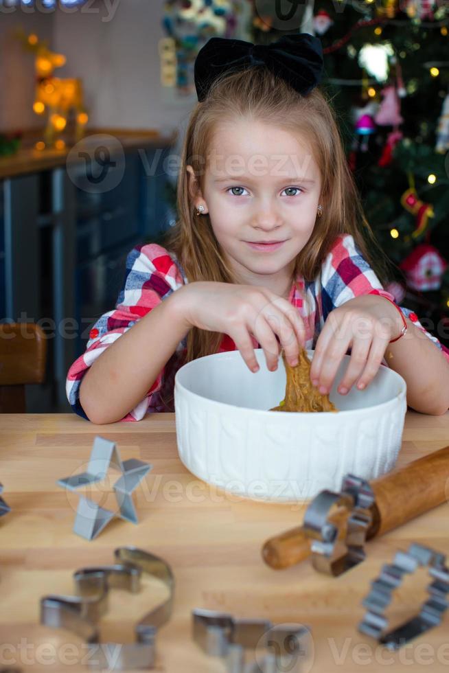 Little girl baking gingerbread cookies for Christmas at home kitchen photo