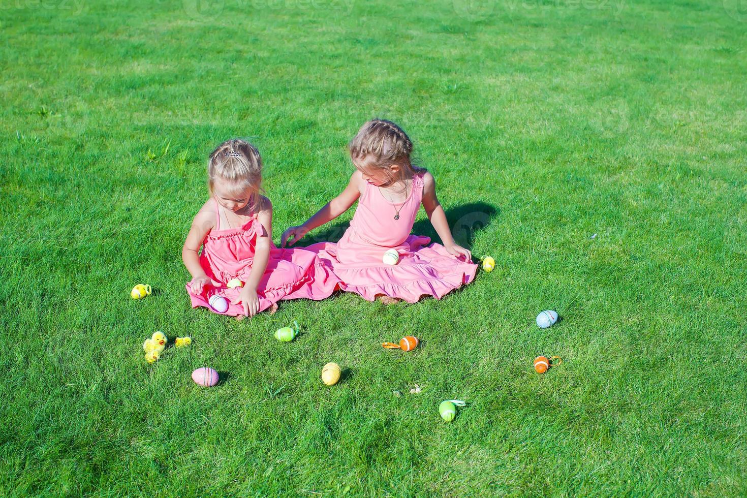 Adorable little girls playing with Easter Eggs on green grass photo