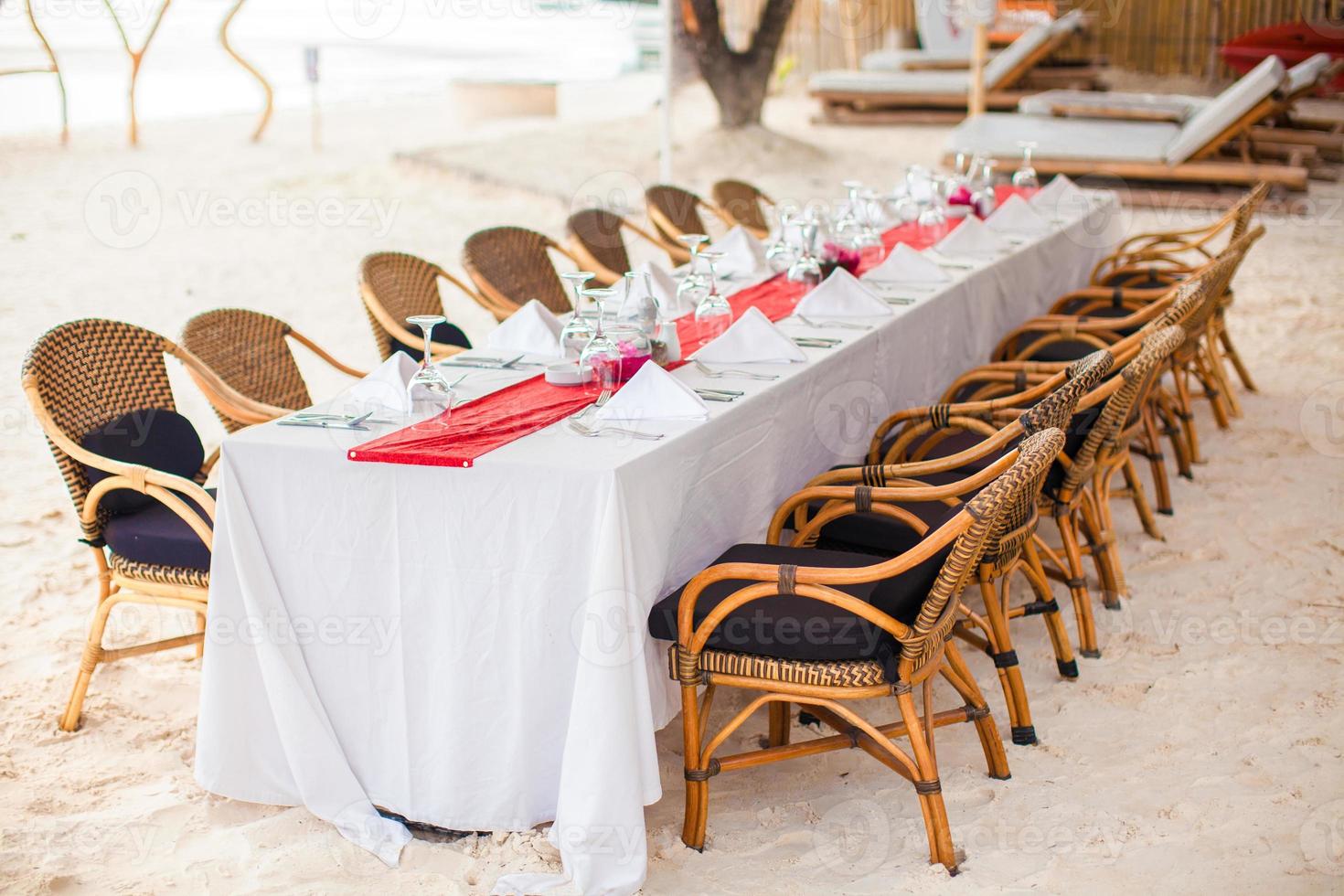 Summer empty open air table set for banquet on beach at sunset photo