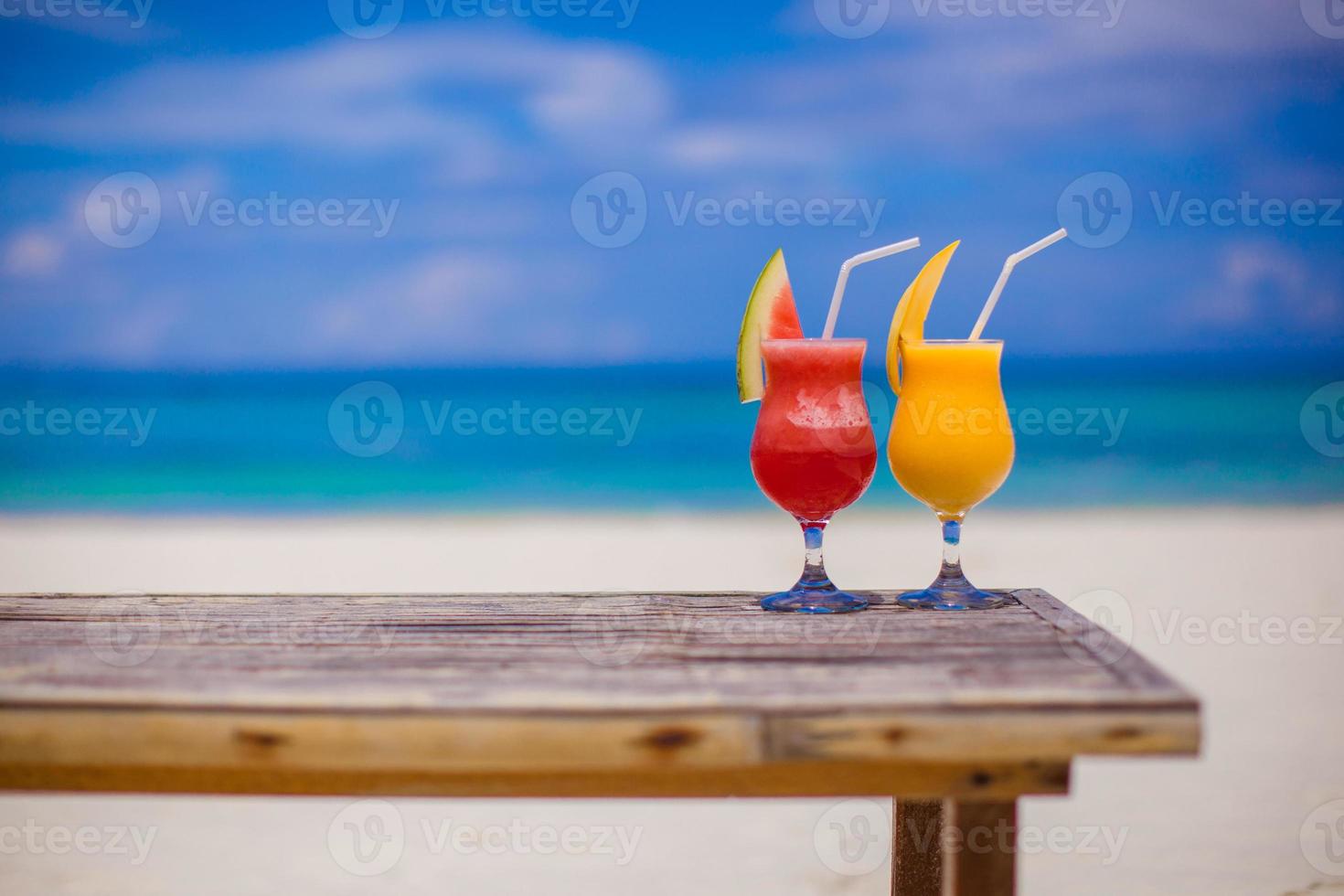 Fresh watermelon and mango cocktails on woodem table background of stunning turquoise sea photo