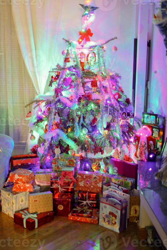 Lighted Christmas tree with presents underneath in living room photo