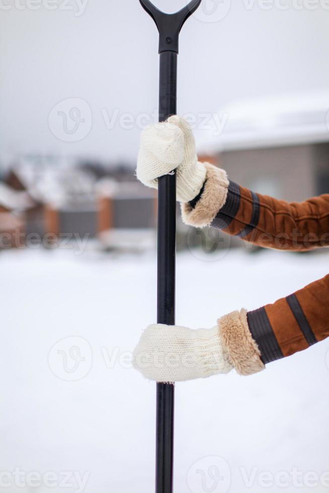 Snow shovel in female hands on a winter day photo
