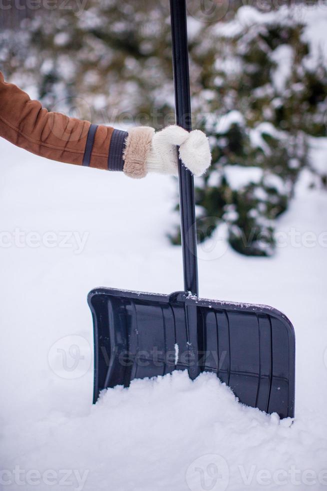 Metal shovel in hands of a young woman into the snow on winter day photo