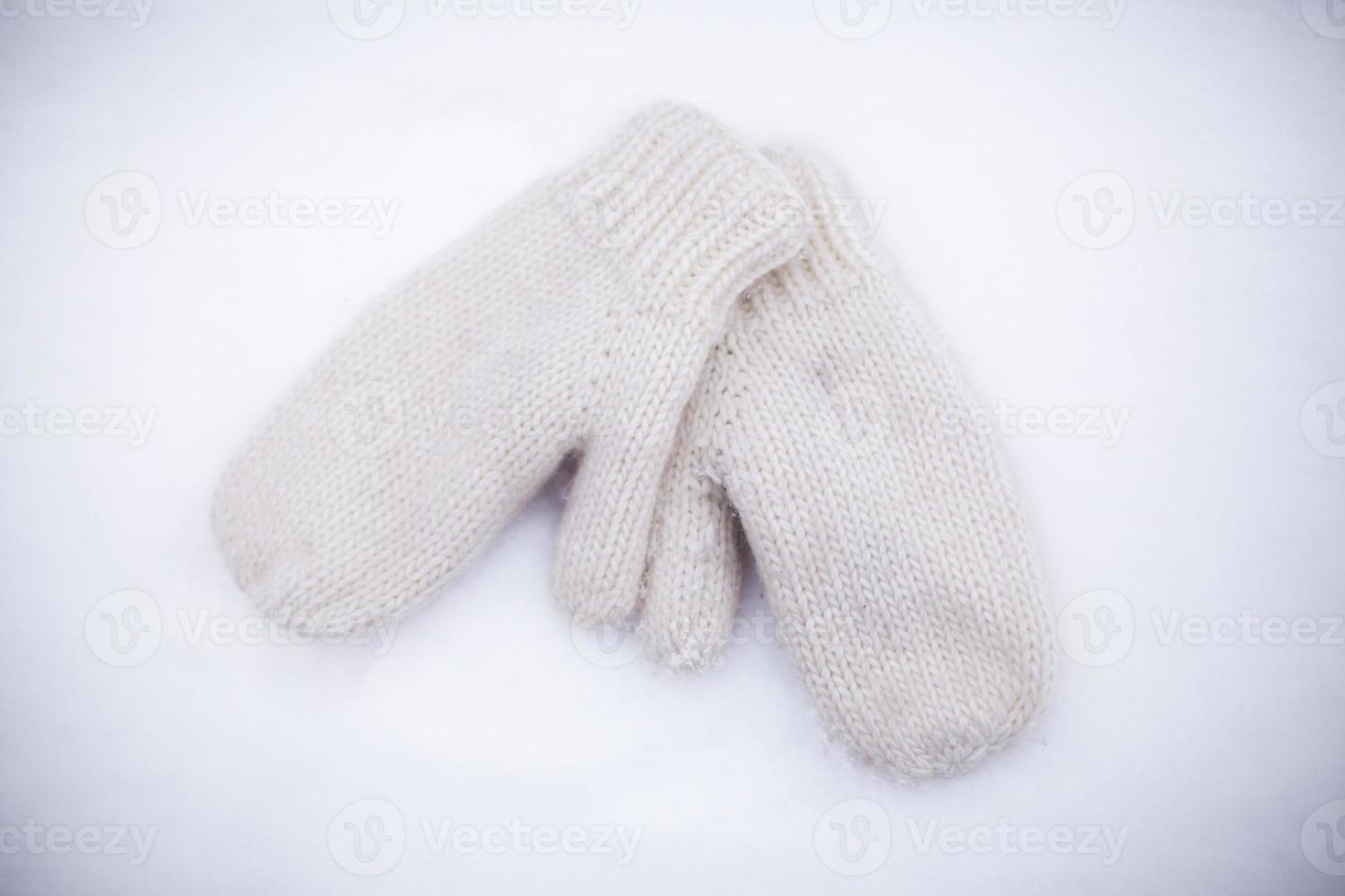 Soft, warm, knitted mittens on the white snow photo
