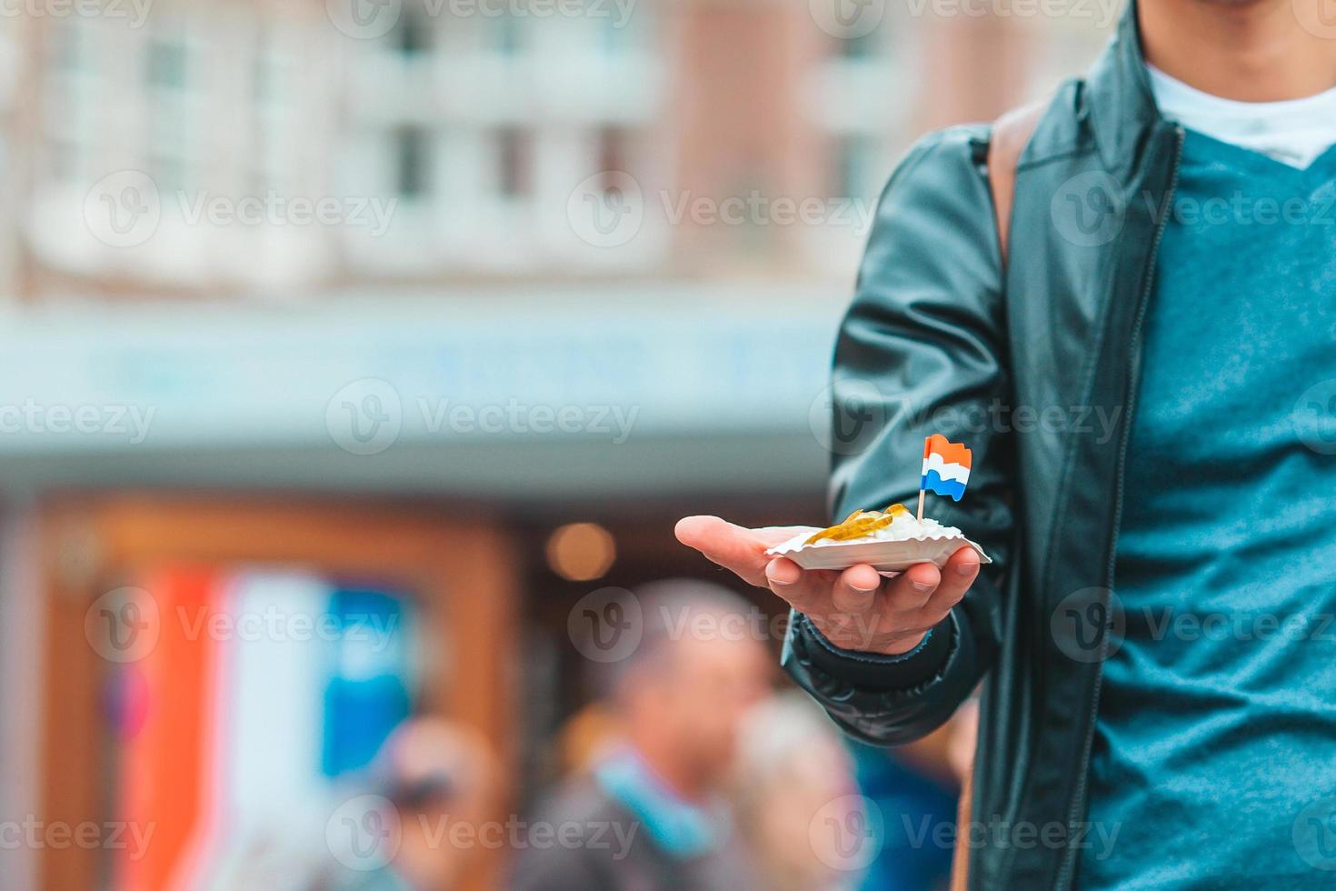 Tasty fresh herring with onion and netherland flag on the water channel background in Amsterdam. Traditional dutch food photo