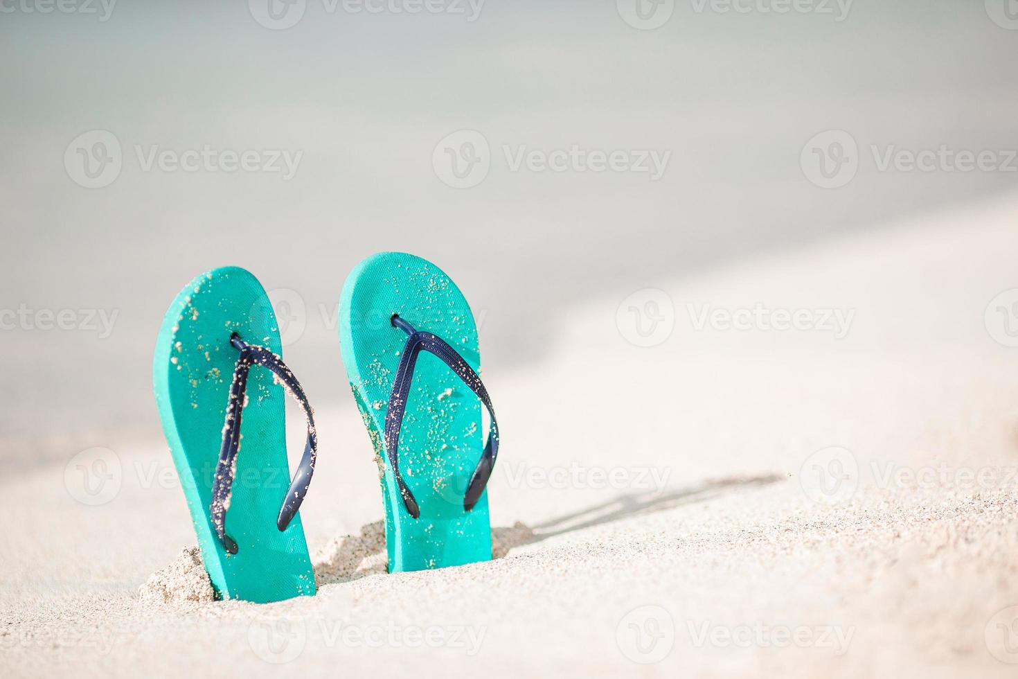 Summer mint flip flops with sunglasses on white beach photo