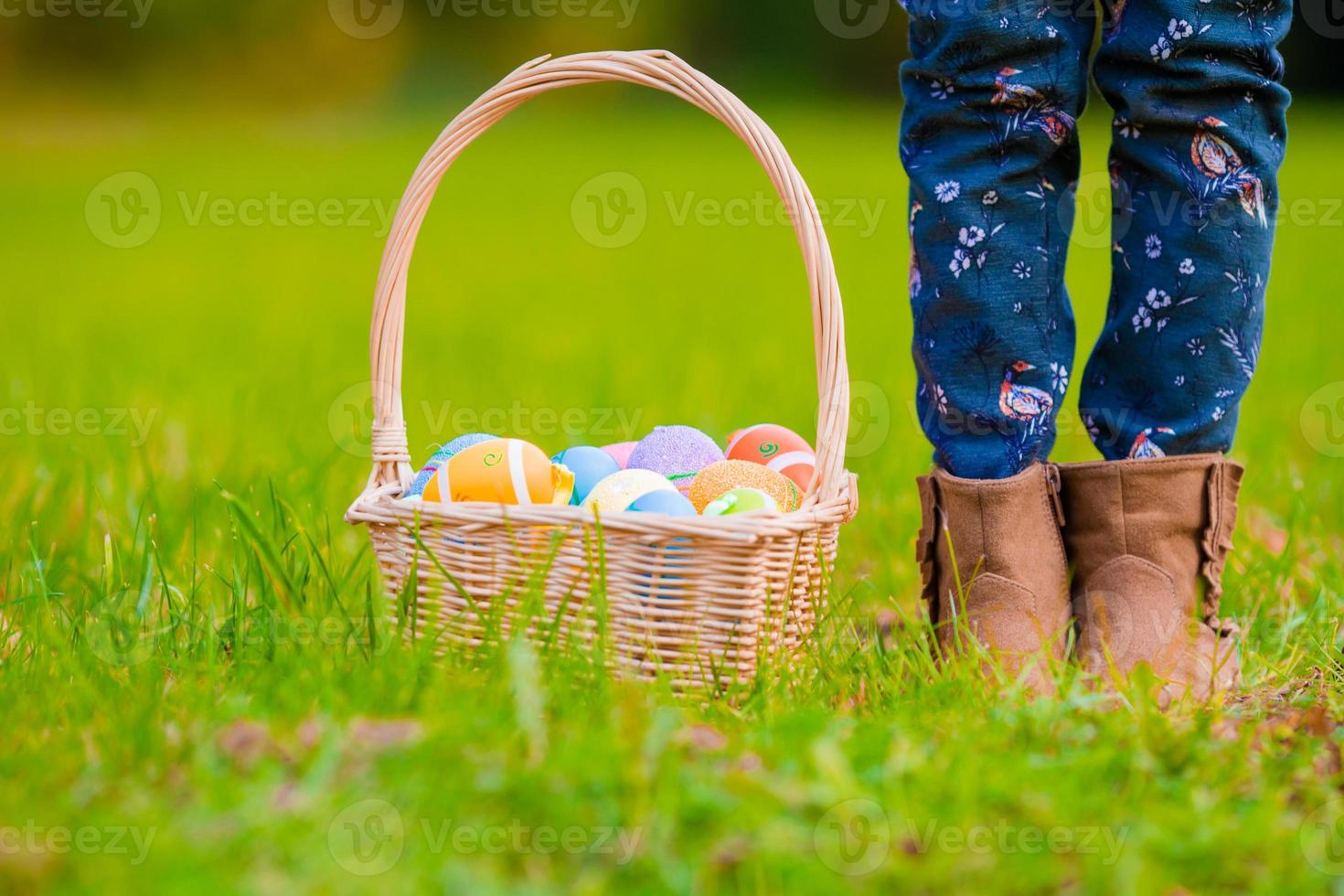Close up colorful Easter eggs in a basket on the grass photo