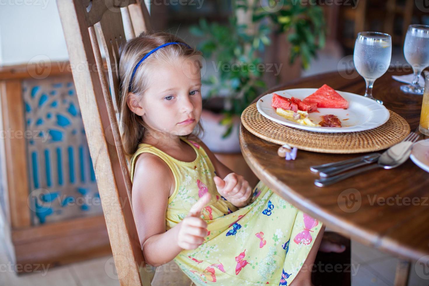 Adorable little girl having breakfast in exotic resort photo