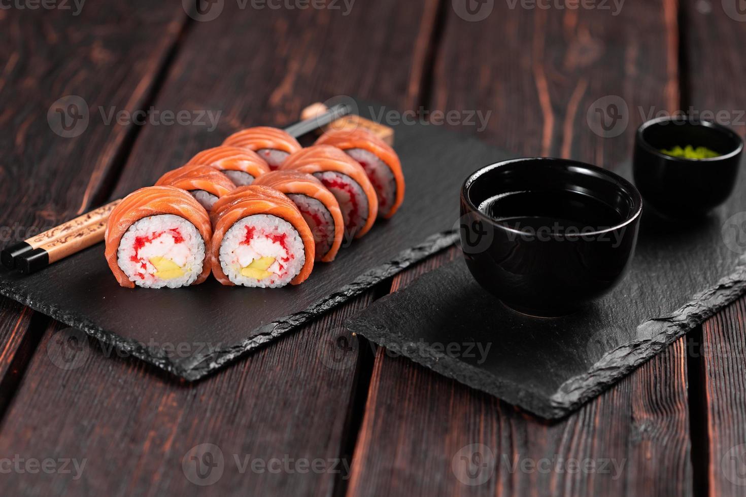 Sushi roll philadelphia with salmon and avocado and cream cheese, caviar on black background close-up. Sushi menu. Japanese food concept photo