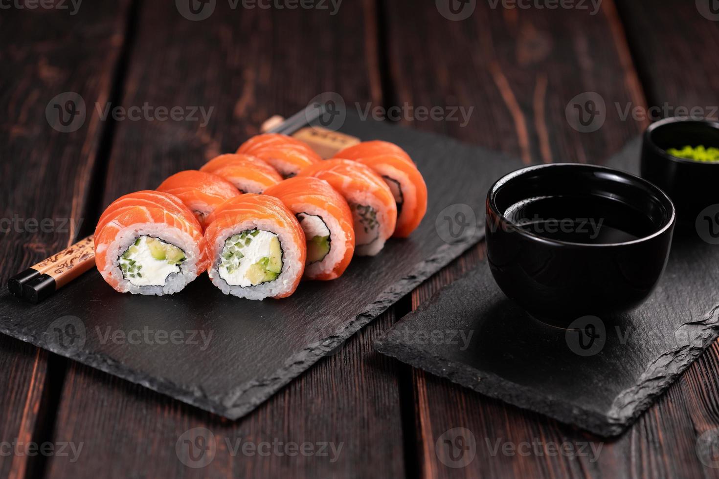 Sushi roll philadelphia with salmon and cucumber with avocado and cream cheese on black background. Sushi menu. Japanese food concept photo