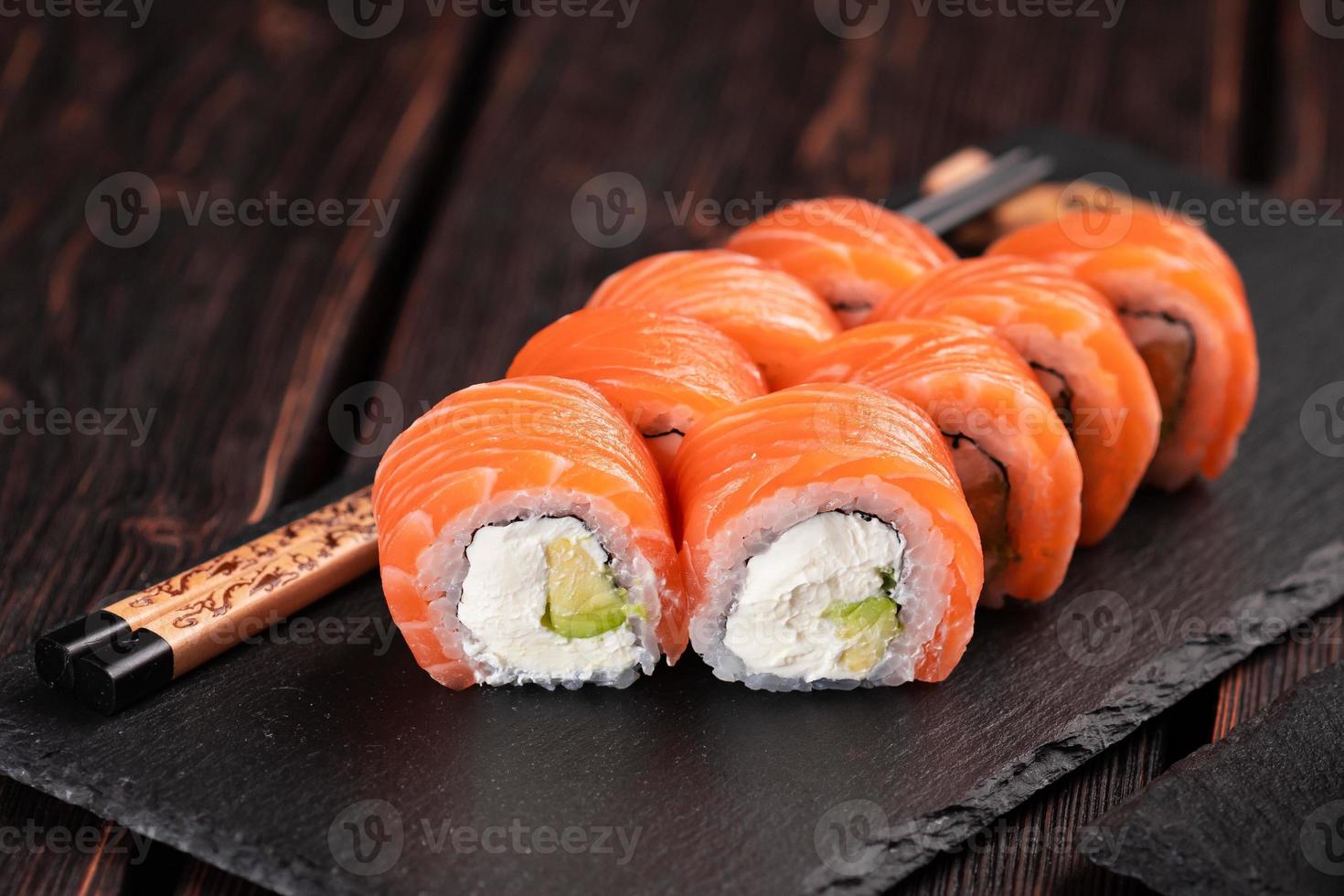 Sushi roll philadelphia with salmon and cucumber and cream cheese on black background. Sushi menu. Japanese food concept photo