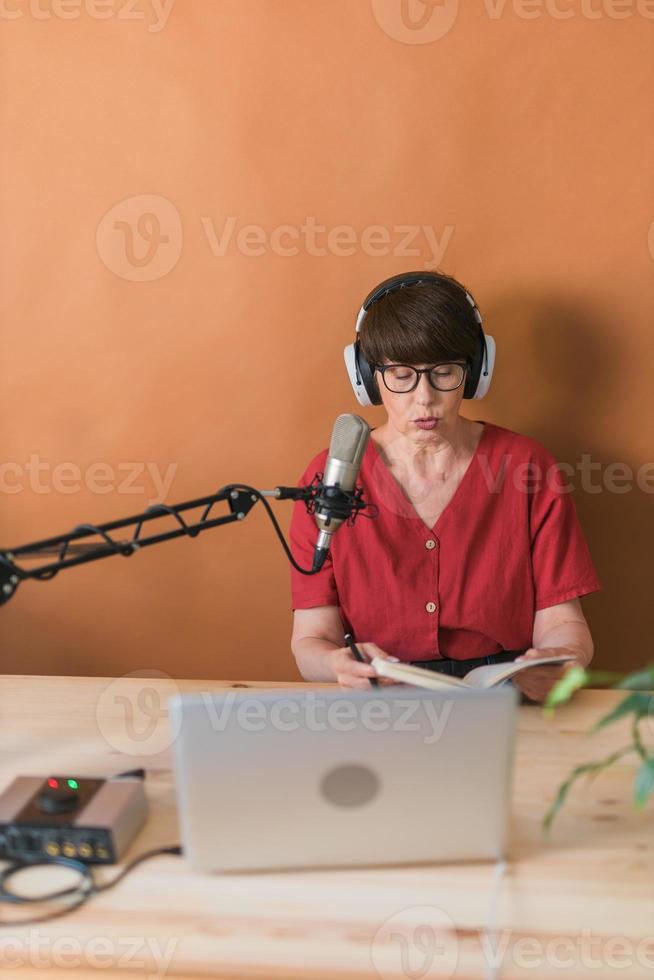 presentadora de radio de mediana edad hablando en el micrófono y leyendo noticias - concepto de transmisión de radio en línea foto