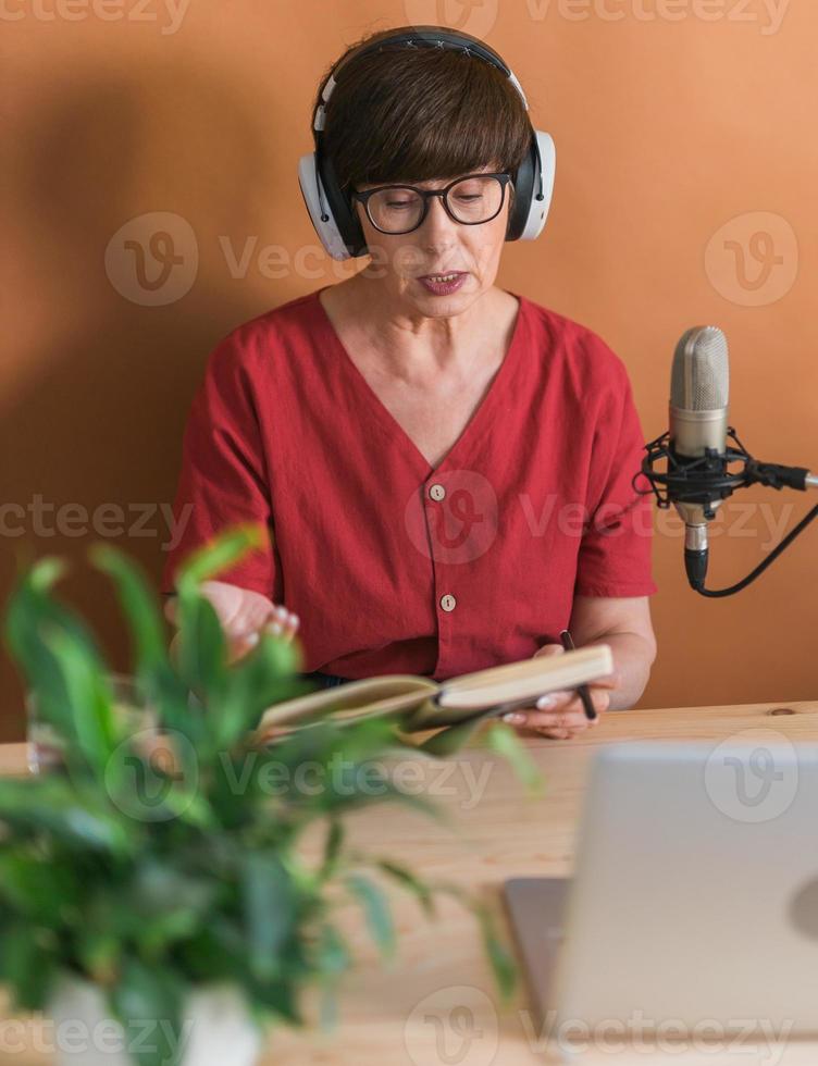 Middle-aged woman radio host making podcast recording for online show - broadcast and dj concept photo