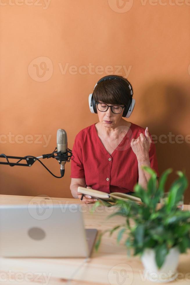 presentadora de radio de mediana edad hablando en el micrófono y leyendo noticias - concepto de transmisión de radio en línea foto