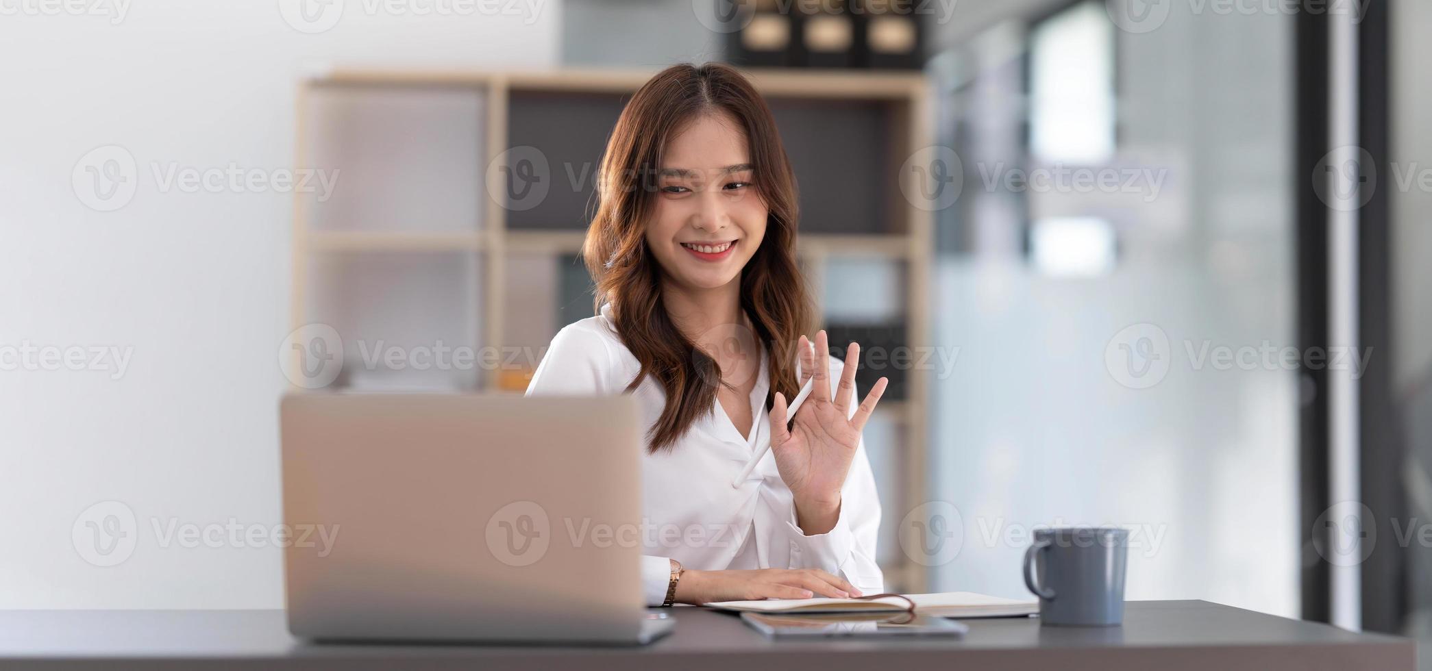 mujer asiática que trabaja en el cargo y discute con un socio comercial a través de una videollamada de una computadora portátil, una joven mujer de negocios asiática es ejecutiva de negocios, fundadora ejecutiva de inicio. concepto de negocio de inicio. foto