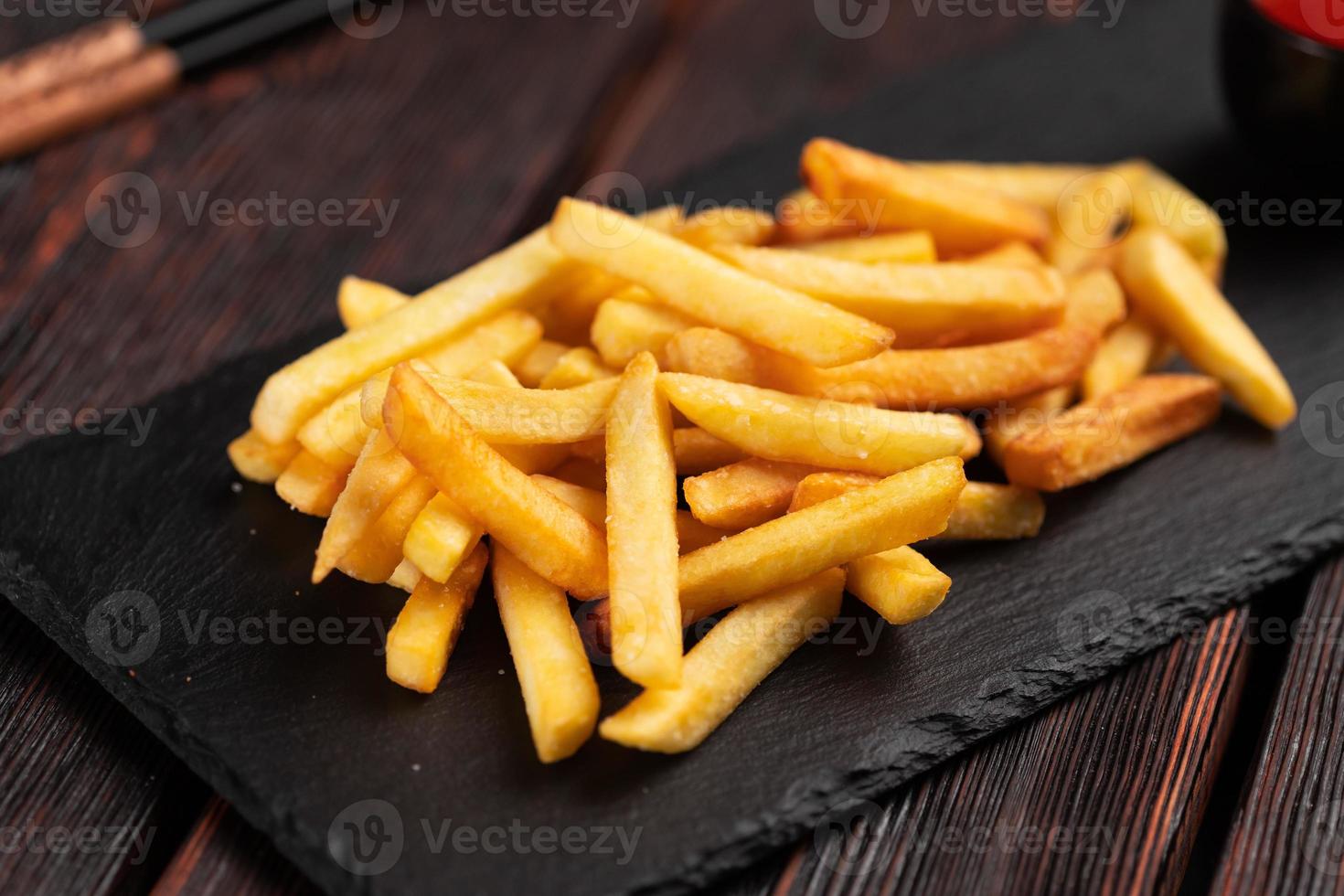 French fries on dark wooden background - fast food and unhealthy eat concept photo
