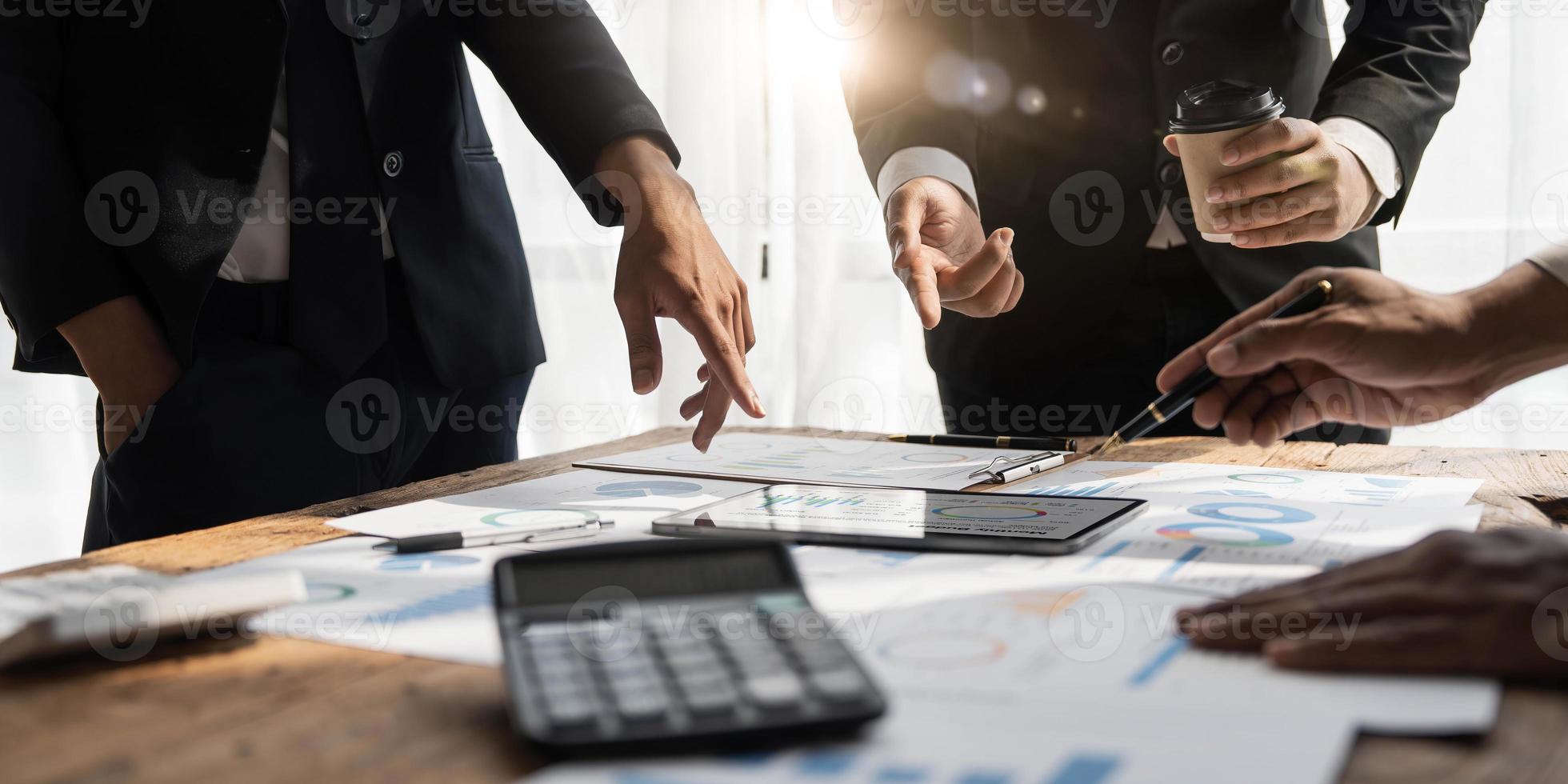 gente de negocios reunida usando computadora portátil, calculadora, cuaderno, papel gráfico del mercado de valores para planes de análisis para mejorar la calidad el próximo mes. conferencia discusión concepto corporativo foto