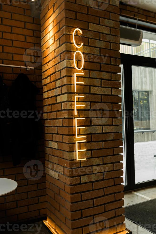 Coffee neon sign emblem in neon style on brick wall background. Coffee shop photo