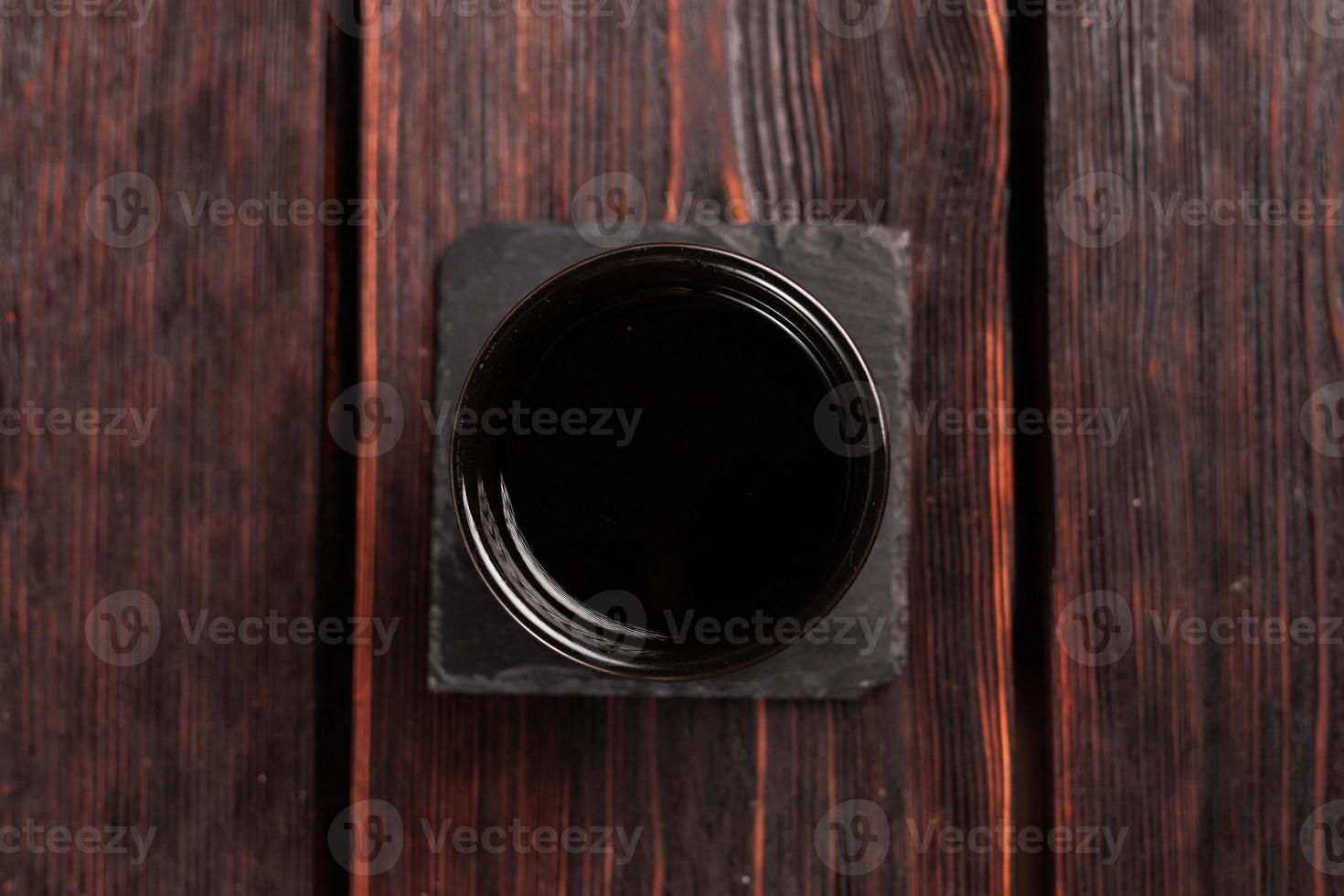 Bowl with soy sauce on wooden table, top view photo