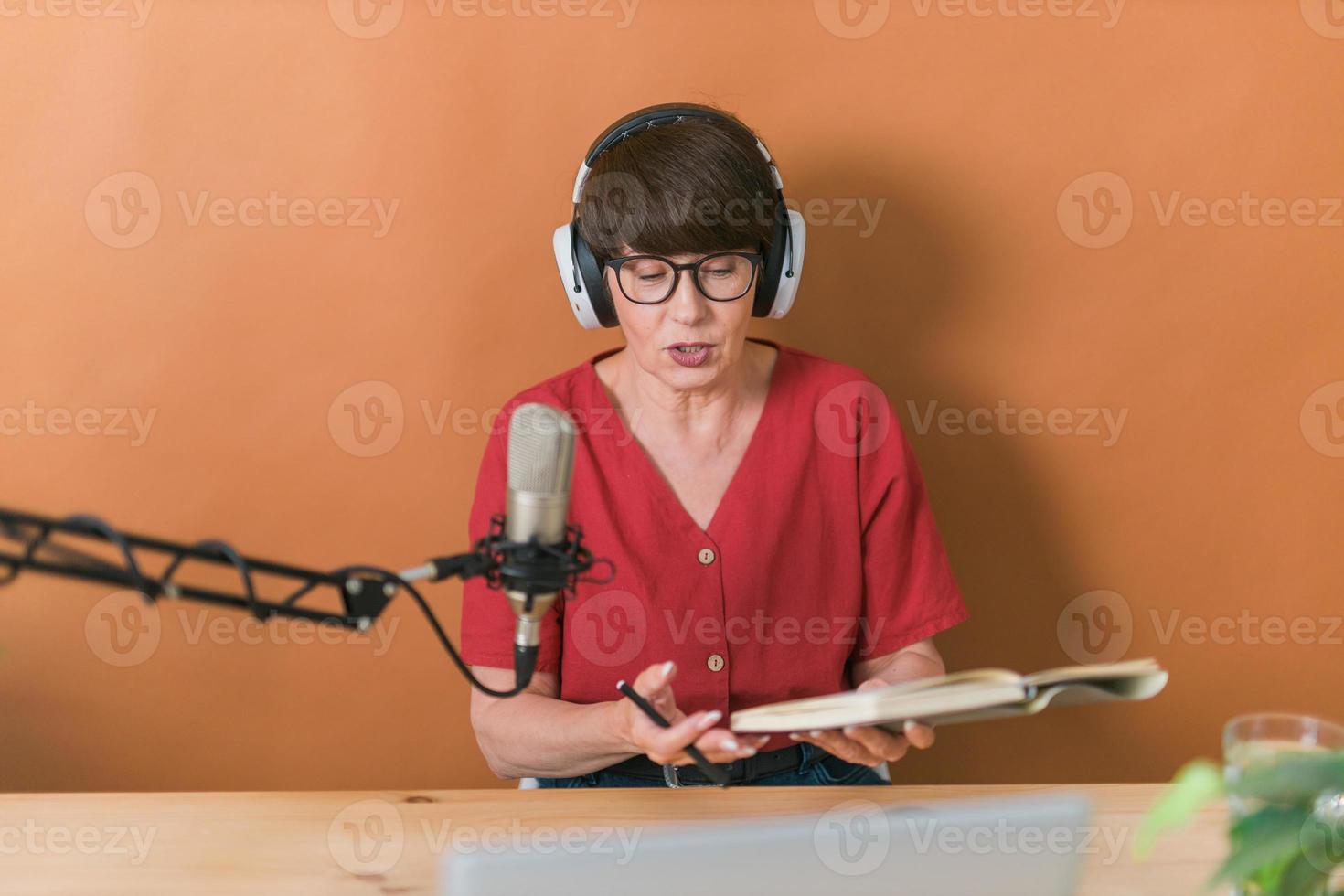 retrato de una mujer madura usando audífonos y hablando en una estación de radio en línea - podcast y concepto de transmisión foto