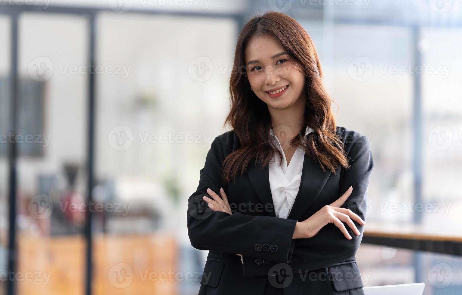 encantadora joven empresaria asiática de pie en la oficina. mirando a la cámara. foto