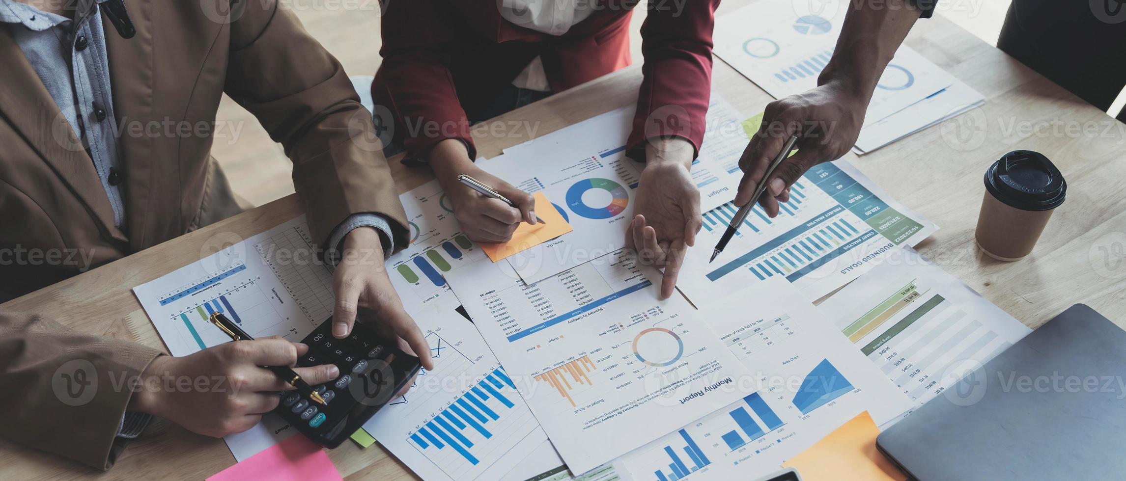 gente de negocios reunida usando computadora portátil, calculadora, cuaderno, papel gráfico del mercado de valores para planes de análisis para mejorar la calidad el próximo mes. conferencia discusión concepto corporativo foto