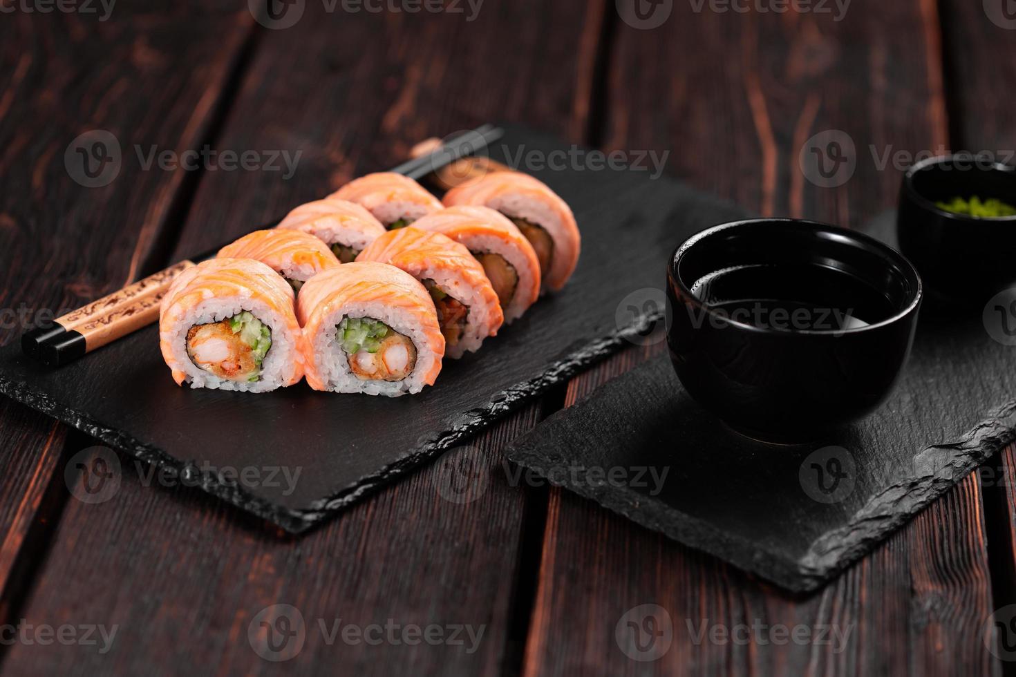 Sushi roll philadelphia with crab and cucumber and cream cheese, caviar on black background close-up. Sushi menu. Japanese food concept photo