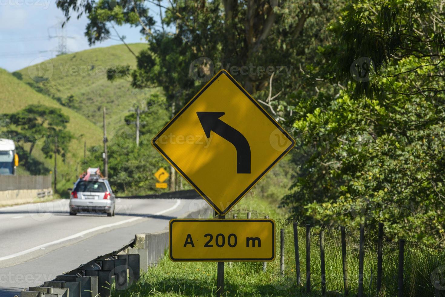 yellow road sign signaling a forward curve on a road photo