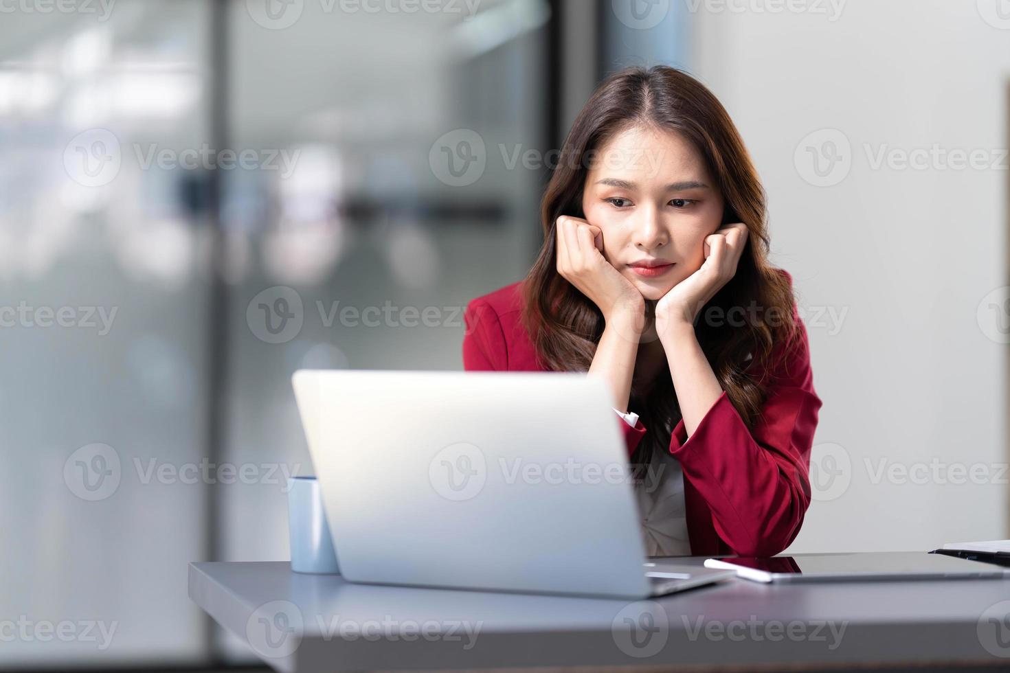 mujer asiática pensando mucho preocupada por la solución de problemas en línea mirando la pantalla de la computadora portátil, preocupada mujer de negocios asiática seria enfocada en resolver tareas difíciles de la computadora foto