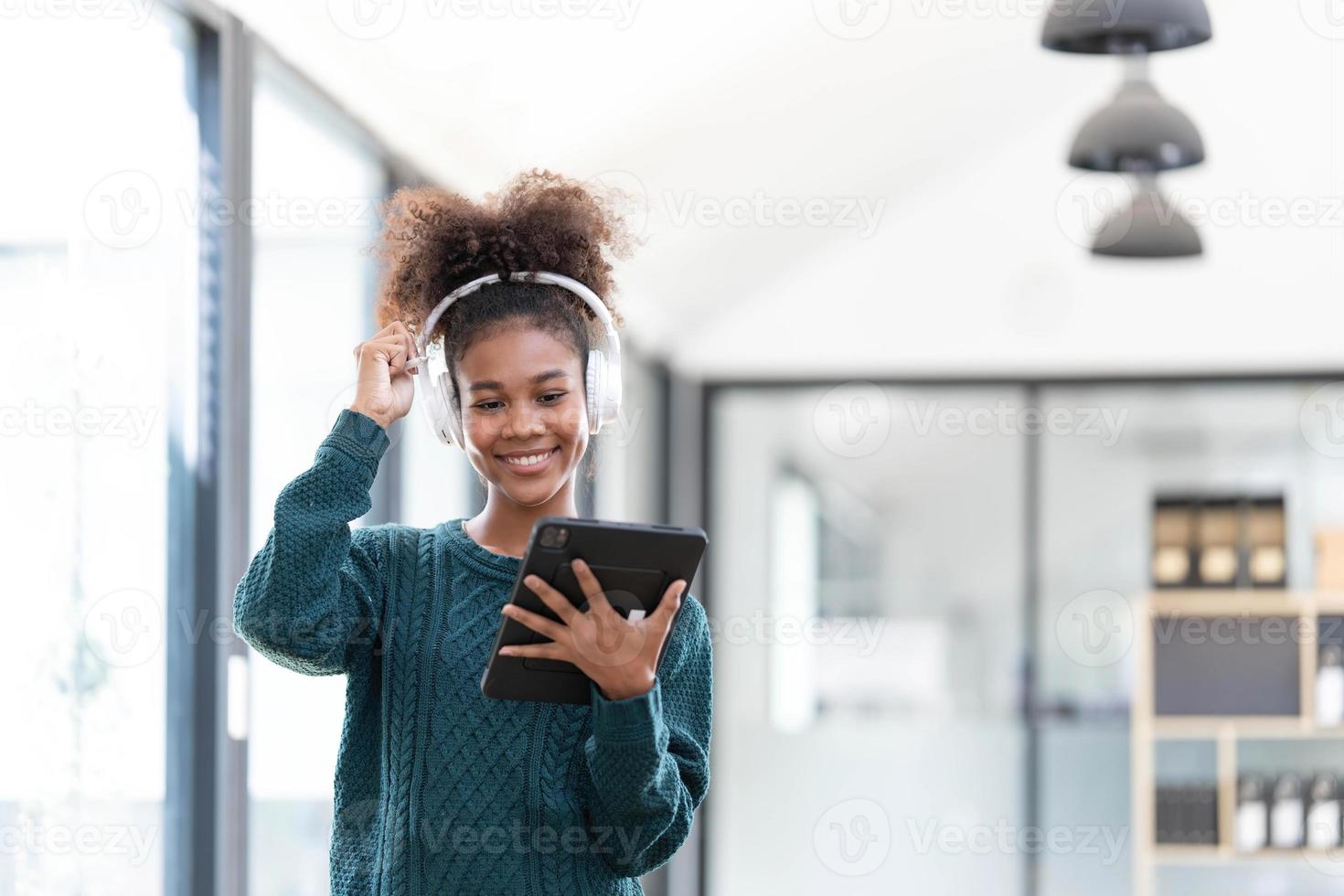 retrato de una joven negra sonriente escuchando música con auriculares y tableta digital foto