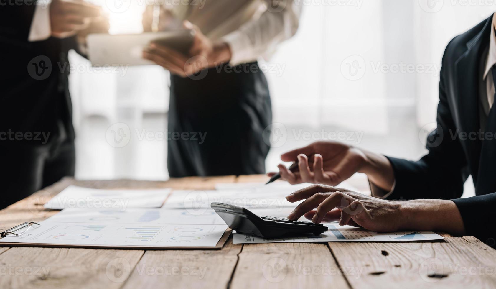 gente de negocios reunida usando computadora portátil, calculadora, cuaderno, papel gráfico del mercado de valores para planes de análisis para mejorar la calidad el próximo mes. conferencia discusión concepto corporativo foto