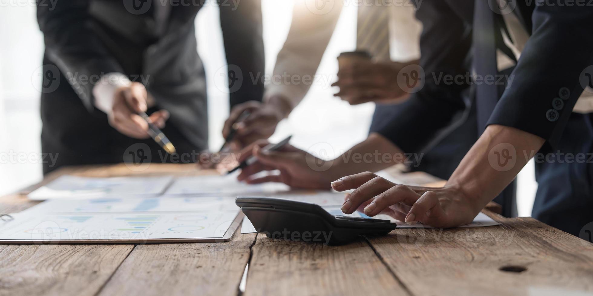 gente de negocios reunida usando computadora portátil, calculadora, cuaderno, papel gráfico del mercado de valores para planes de análisis para mejorar la calidad el próximo mes. conferencia discusión concepto corporativo foto