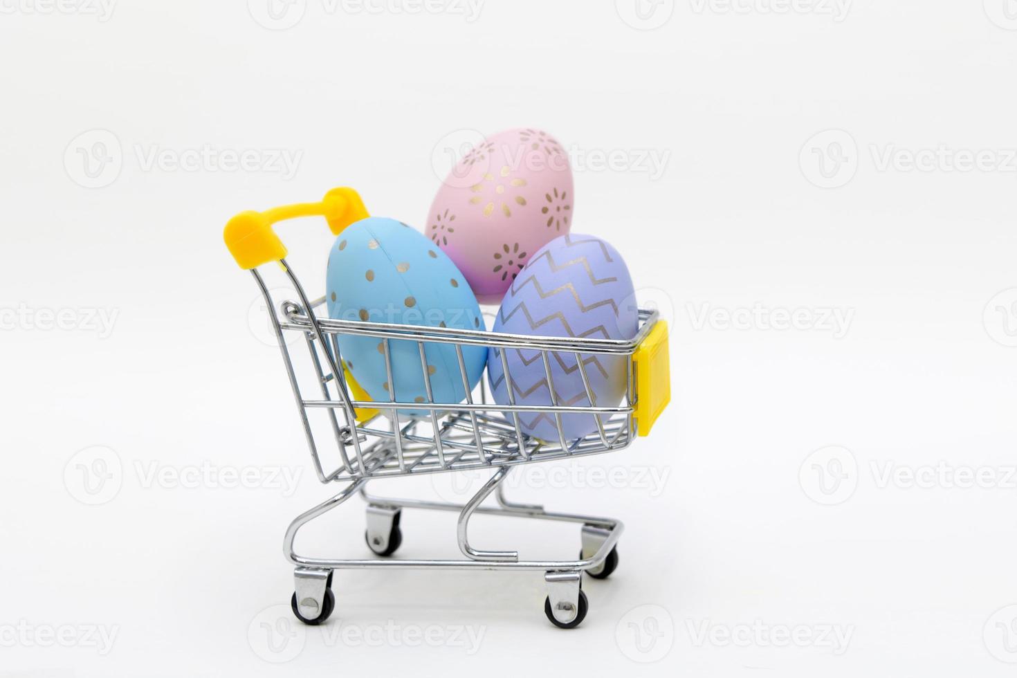 Colorful easter eggs in shopping cart on grey background. Copy space. photo